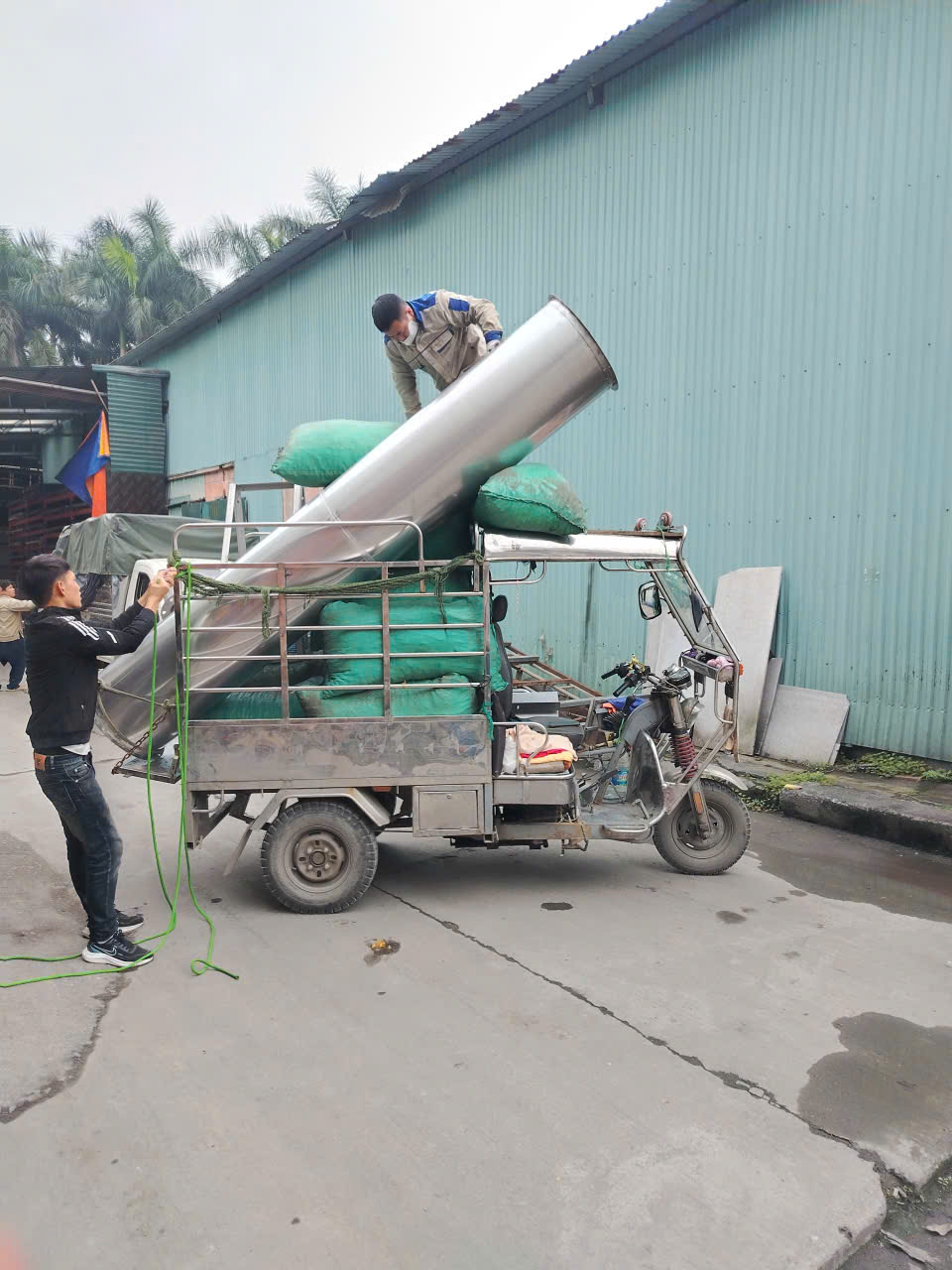 Nhân viên chằng buộc hàng dài trên xe ba gác